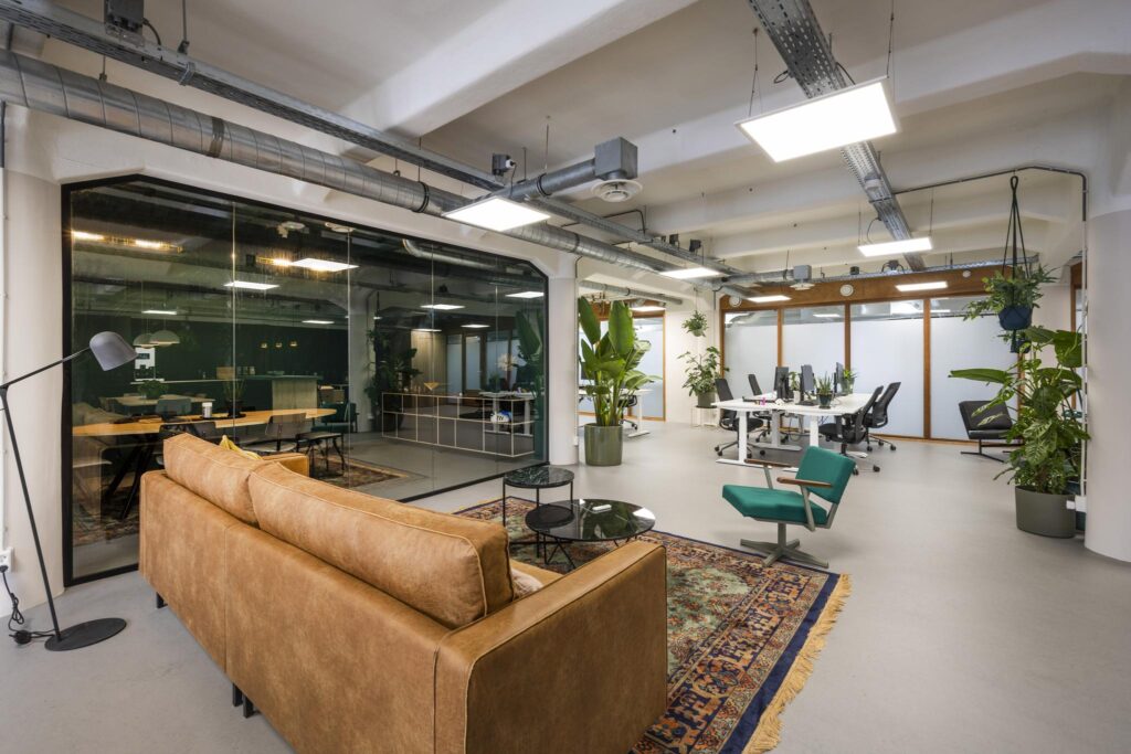 Modern open-plan office interior on Van Diemenstraat with lounge area, workstations, and indoor plants.